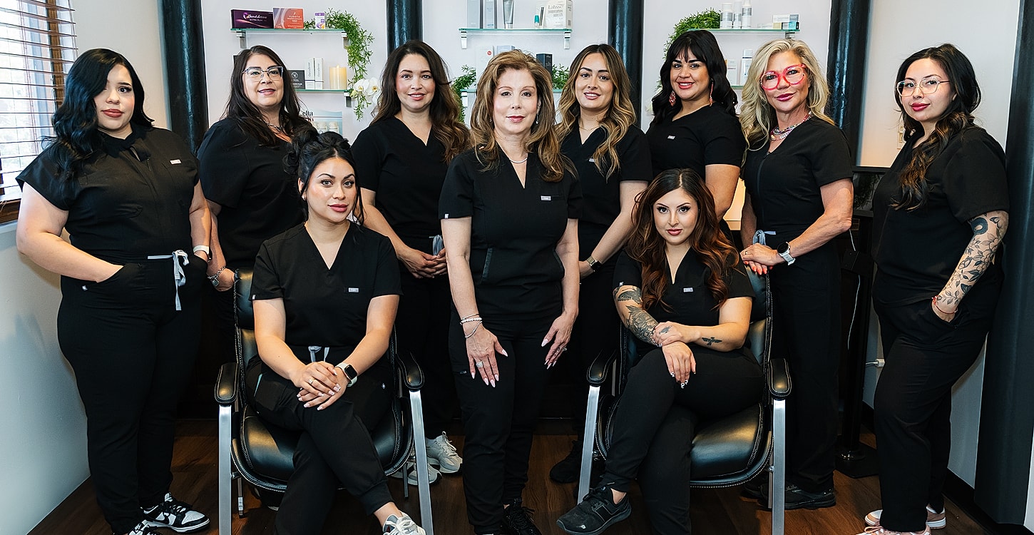 Group of women in black scrubs smiling together.