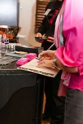 Person writing on a menu at an event.
