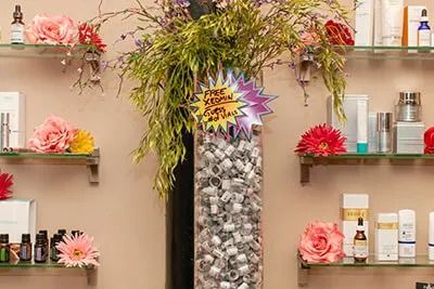 Beauty products display with promotional sign and flowers.