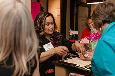Woman assisting customers at a reception desk.
