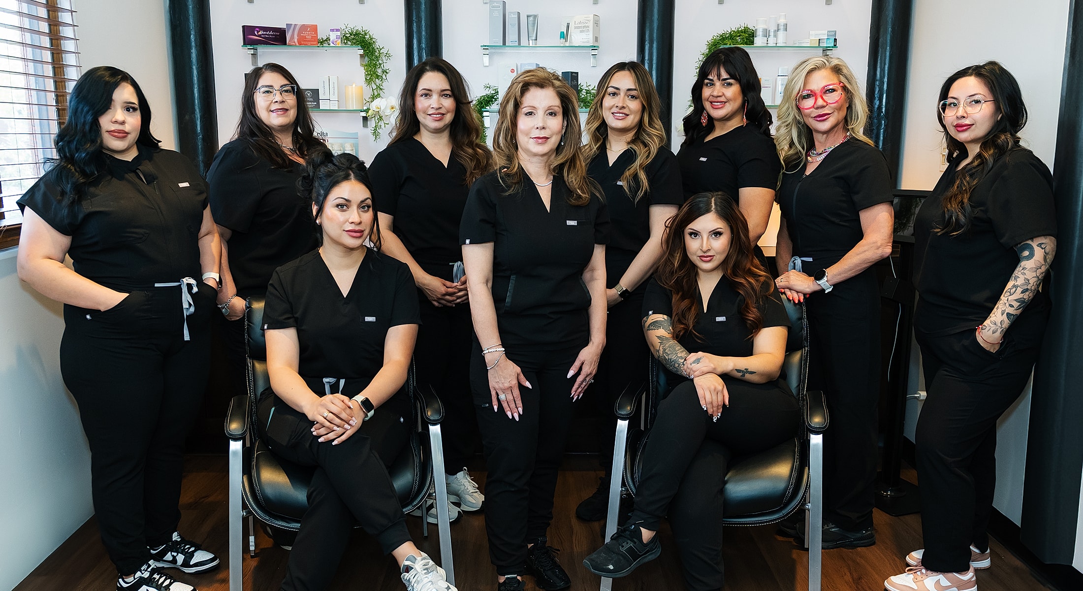 Group of women in black scrubs smiling together.