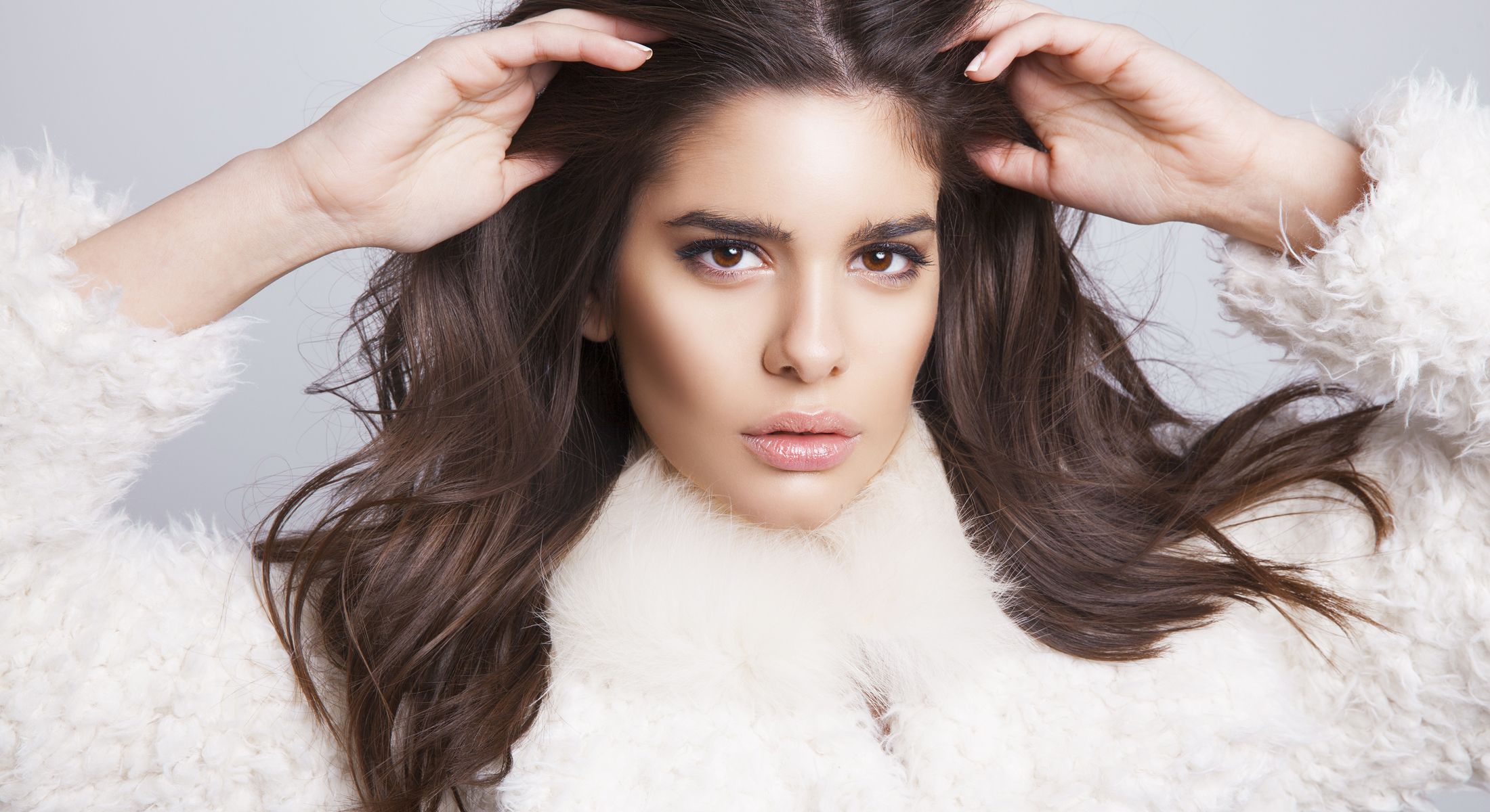 Model in white fur coat with long hair.