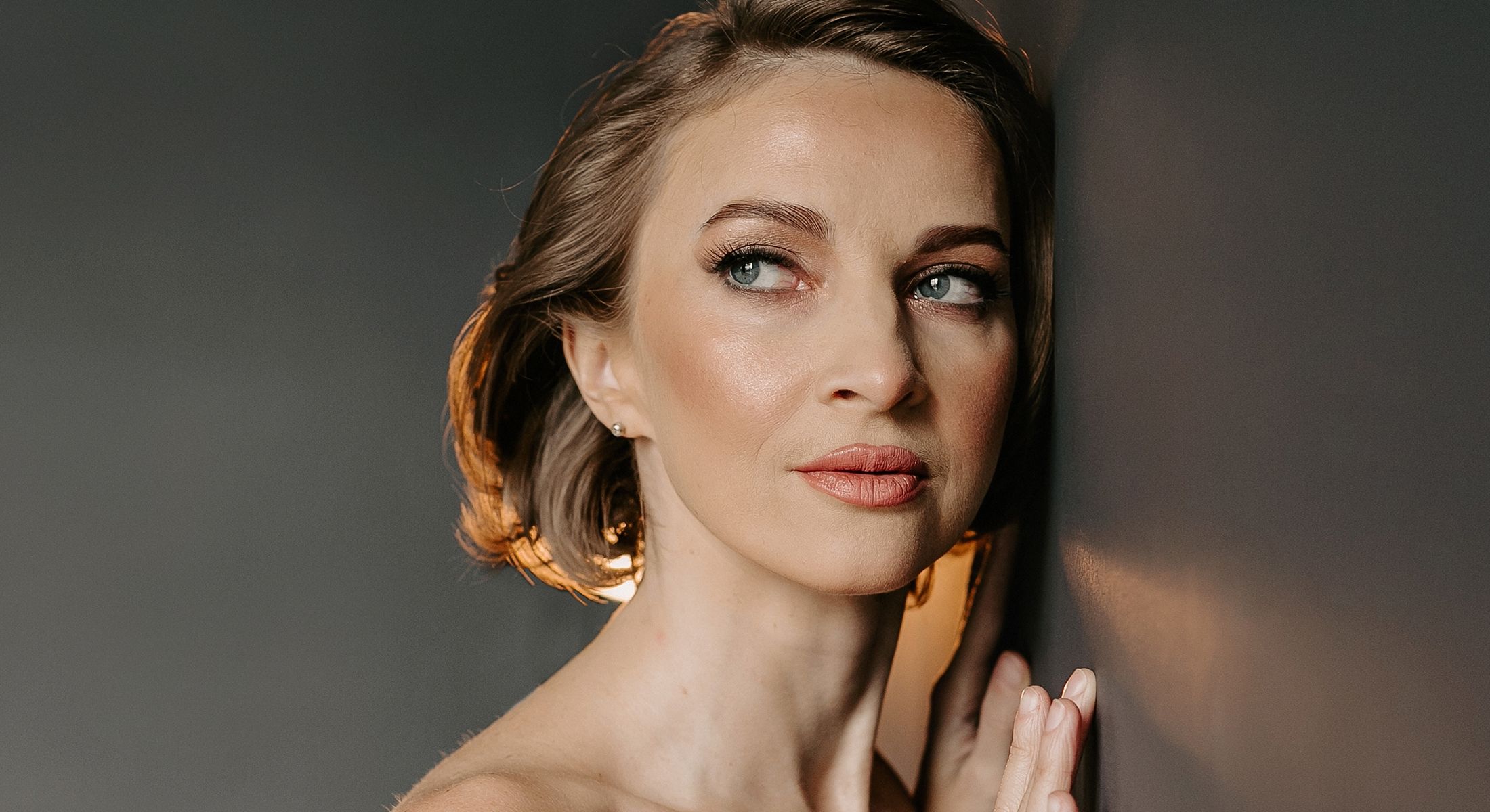 Woman with short hair leaning against a wall.
