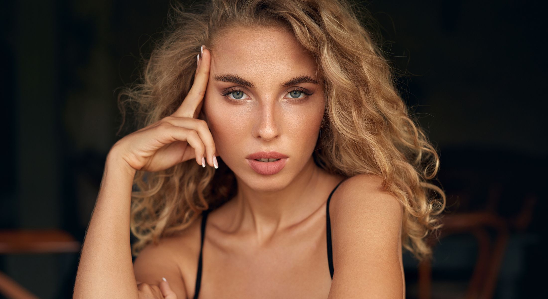 Woman with curly hair and thoughtful expression.