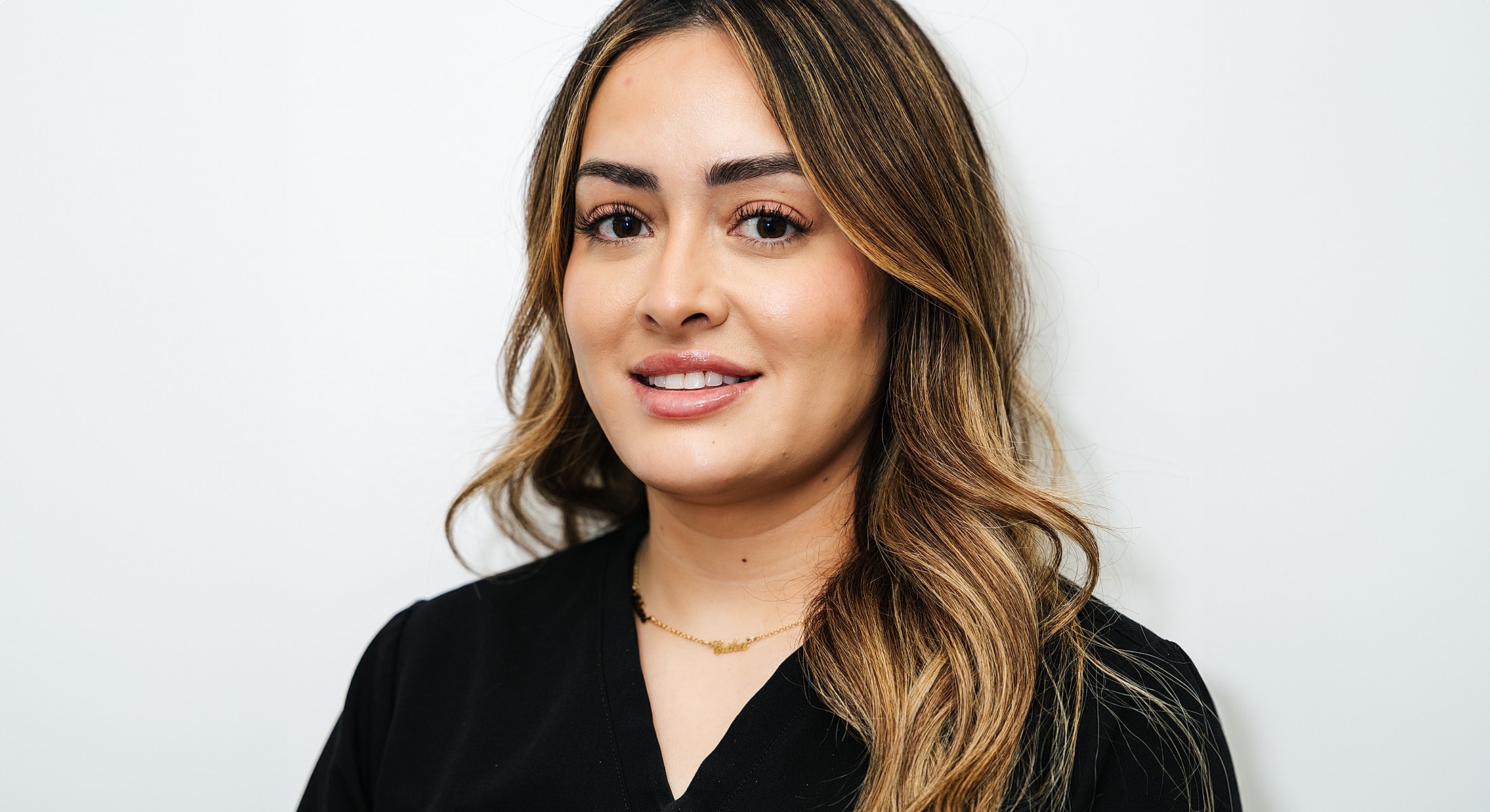 Smiling woman with long hair and necklace.