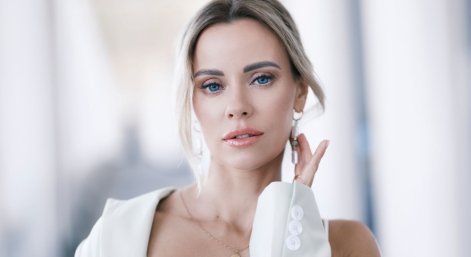 Woman with striking blue eyes and elegant attire.
